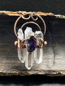 Detail eines handgefertigten Bronzeanhängers mit drei weißen Kristallen und Amethyst