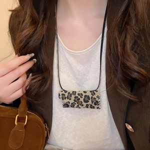 Detail shot of leopard print mini envelope pendant necklace on a brown blazer outfit