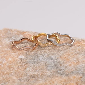 Three wavy stainless steel rings in rose gold, gold, and silver with micro-pave crystals