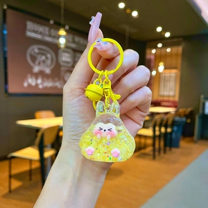 Close-up of cute yellow resin hamster keychain with glitter, small bell, and metal ring
