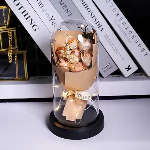 Close-up of champagne roses in a glass dome with warm LED lights and decorative books