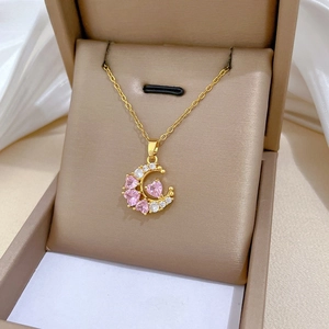 Macro view of gold moon pendant with pink heart gemstones and zircons in a jewelry box