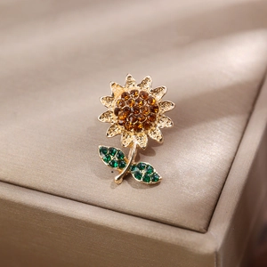 Détail d'une broche tournesol dorée ornée de strass ambre et de cristaux verts brillants