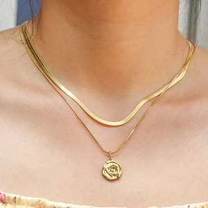 Layered gold herringbone chain necklace featuring a vintage rose embossed coin pendant