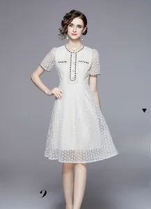Detail of white lace dress with pearl buttons and black-gold woven trim accents