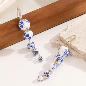 Detail of blue and white porcelain bead earrings with gold hooks and zircon accents