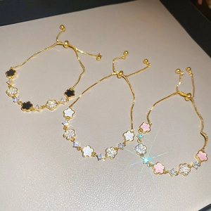 Detailed view of adjustable floral bracelets in black, white, and pink with gold plating