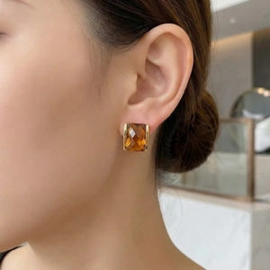 Close-up of amber square cut gemstone earring with 18K gold plated setting on ear