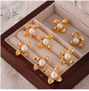 Macro detail of gold-plated flower earrings with white faux pearls in a wooden box