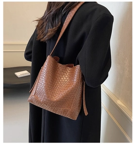 Detail of a brown woven texture shoulder bag with soft PU leather surface and bucket shape