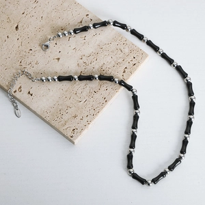 Handmade necklace with black agate stone beads and silver spacers on beige stone plate