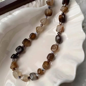 Detailed macro view of faceted agate beaded necklace on a white ceramic shell tray