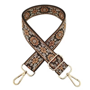 Detailed view of dark brown ethnic guitar strap with floral embroidery and gold metal clips