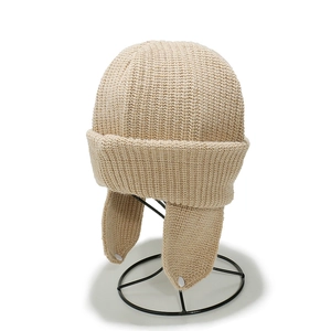 Minimalist beige knit earflap hat for kids with button detail on a display stand