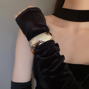 Close-up of a wide polished silver cuff bracelet worn over a black velvet sleeve