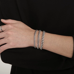 Three silver stainless steel Cuban link bracelets in various widths shown on wrist