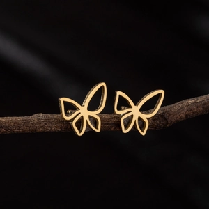 Minimalist golden hollow butterfly stud earrings displayed on a natural wood branch
