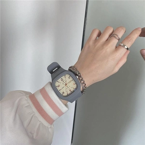 Close-up of a square quartz watch with grey silicone strap and cream dial on wrist