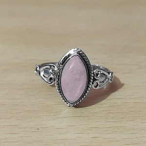 Detail eines Vintage-Marquise-Rings mit lila Stein und Herzmustern auf Holzgrund