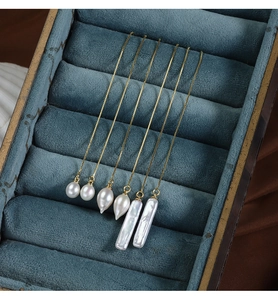 Detailed view of three pairs of baroque pearl earrings in a blue velvet jewelry box