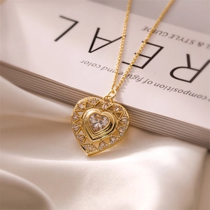 Detail of a gold heart pendant necklace with micro-set zircons on beige silk