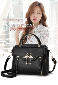 Close-up of black lychee leather handbag with golden swan clasp and pearl detail