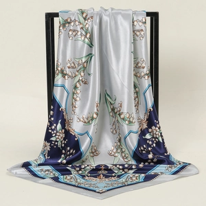 Detail of square silk scarf with lily of the valley print and satin finish on a display