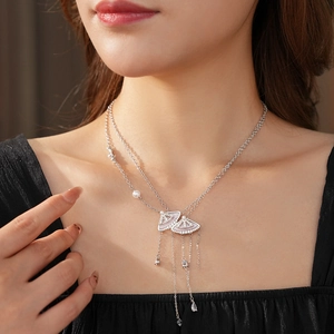 Detail of fan-shaped pendant necklace with white stones and pearls on a model neck
