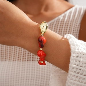 Détail d'un bracelet en perles acryliques avec perles rouges irrégulières et accents dorés