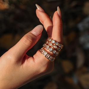 Detail of stacked gold zircon rings featuring pear and rectangular cut stones on finger