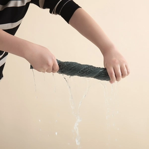 Thick combed cotton towel in dark grey being wrung out showing high water absorption