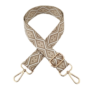 Detail of geometric jacquard bag strap with gold metal hooks and adjustable buckle