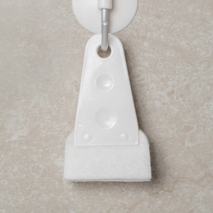 White fan and keyboard gap cleaning brush with sponge pad hanging on a suction cup hook