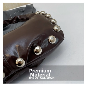 Detailed macro view of dark coffee leather handbag featuring silver spherical metal studs