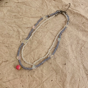 Detail of double-layer beaded necklace with pink rose pendant and butterfly accents