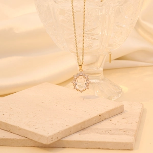 Detail of gold oval pendant with small diamonds on beige silk and stone textures