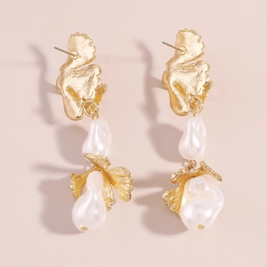 Detail of baroque pearl earrings with golden metallic leaf-like texture and petal design