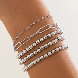Detail shot of silver layered chain and bead bracelets stacked on a model wrist