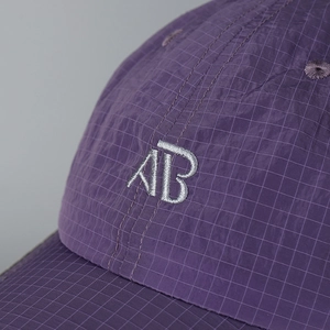 Detailed view of quick-dry plaid fabric and 'AB' embroidery on purple baseball cap