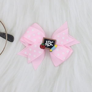 Detail of pink polka dot hair bow clip featuring ABC blackboard and pencil ornament