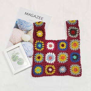 Detailed close-up of handmade crochet granny square patterns on a vintage tote bag