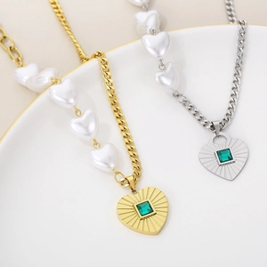Macro detail of heart necklace with green zircon gemstone and white faux pearls