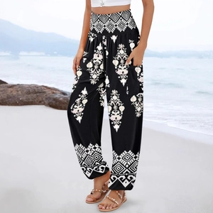 Women's black boho high-waisted harem pants with ethnic print on a sunny beach setting