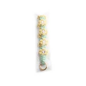 Macro detail of handmade macaron daisy flower knitted keychain with gold metal ring