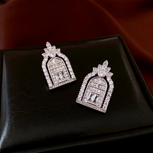 Macro shot of silver arch earrings with cubic zirconia on black leather stand