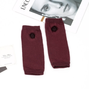 Detail of burgundy knitted arm warmers with thumb holes and soft elastic texture