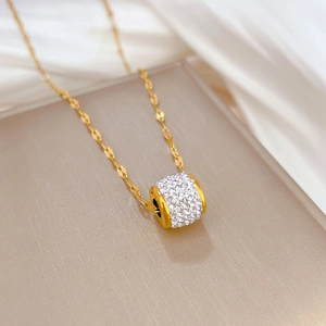 Macro shot of gold cylinder pendant with pavé diamonds on elegant satin background