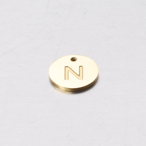Macro shot of 12mm gold stainless steel round charm with engraved letter N for DIY jewelry