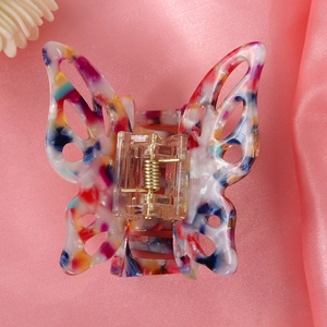 Detailed macro view of butterfly-shaped marble pattern hair claw with gold spring mechanism