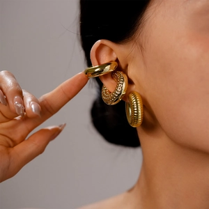 Close-up of three gold ear cuffs with smooth, dotted, and textured metallic finishes